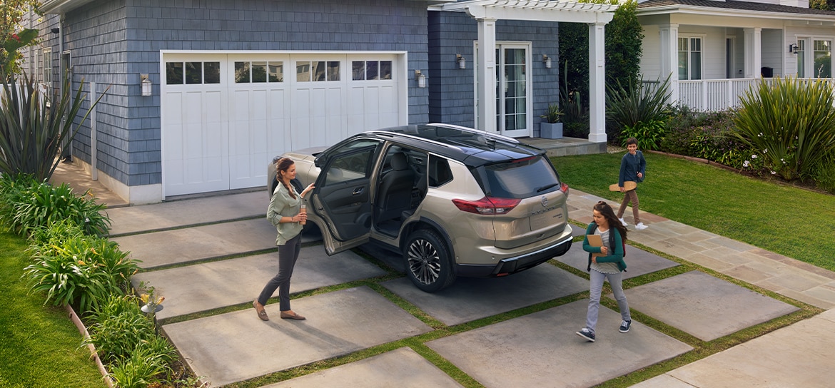 Family unloading a Nissan Rogue SUV in their driveway, showing space and convenience for everyday family life